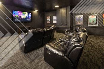 a room with a large screen tv and leather couches